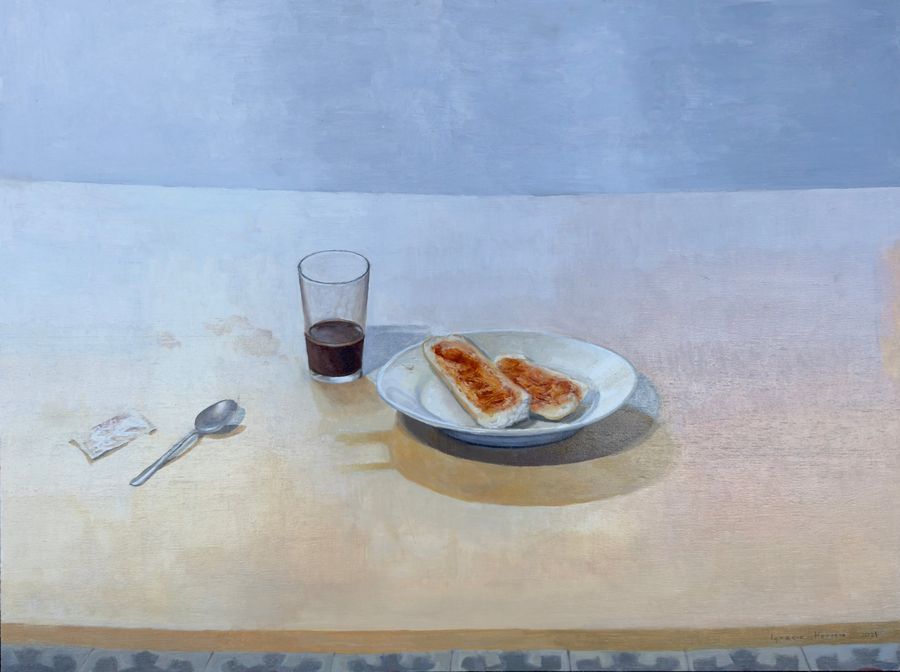 Plato con pan con tomate, un vaso de vino y una cuchara sobre una mesa clara
