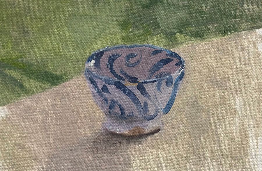 Cuenco de cerámica con dibujos azules sobre una mesa, pintado al aire libre